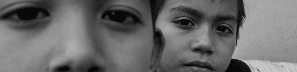 two migrant boys looking at the camera, photo by Lori Barra