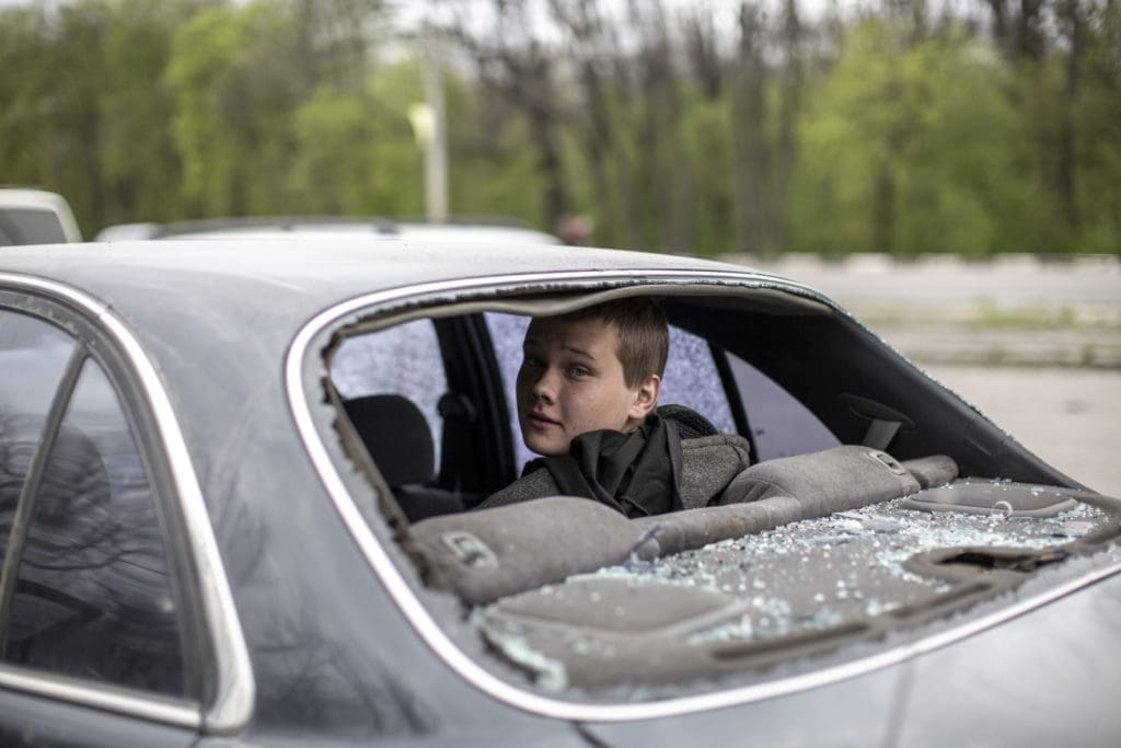 Young boy looks outside in the back of a car.