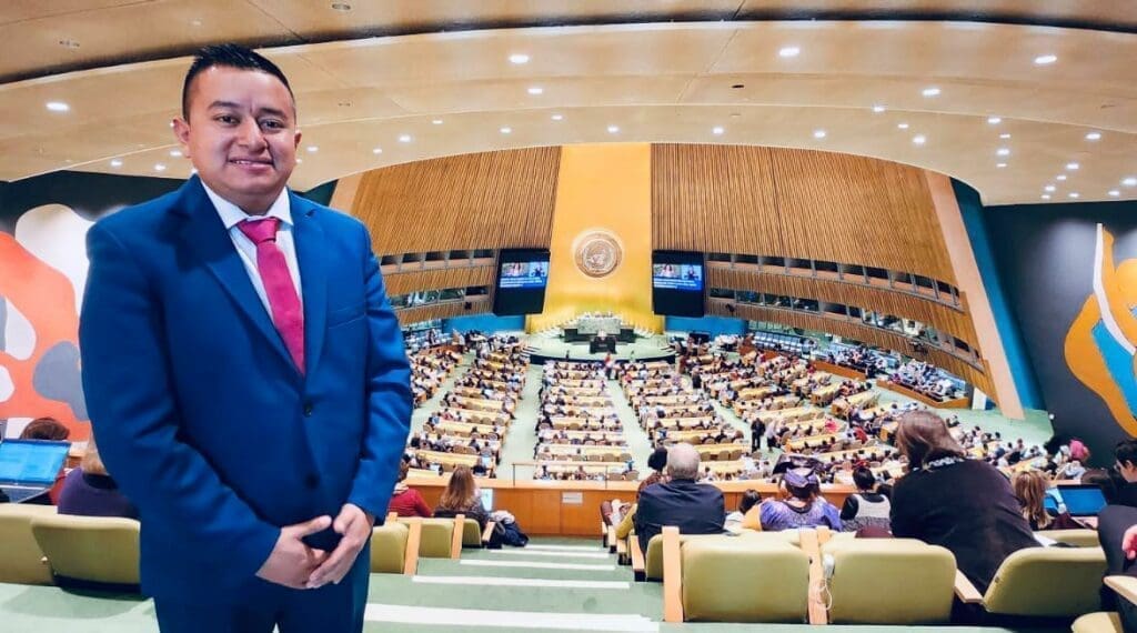 Alexander Morales smiling in a navy suit while he is at the UN Session speaking about a women’s digital empowerment project he helped implement in Guatemala.