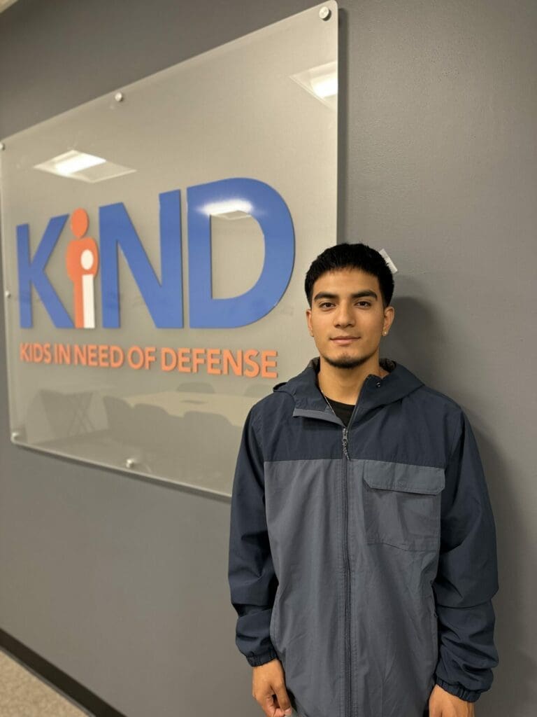 Photo of KIND Client Osmar standing in front of the KIND sign