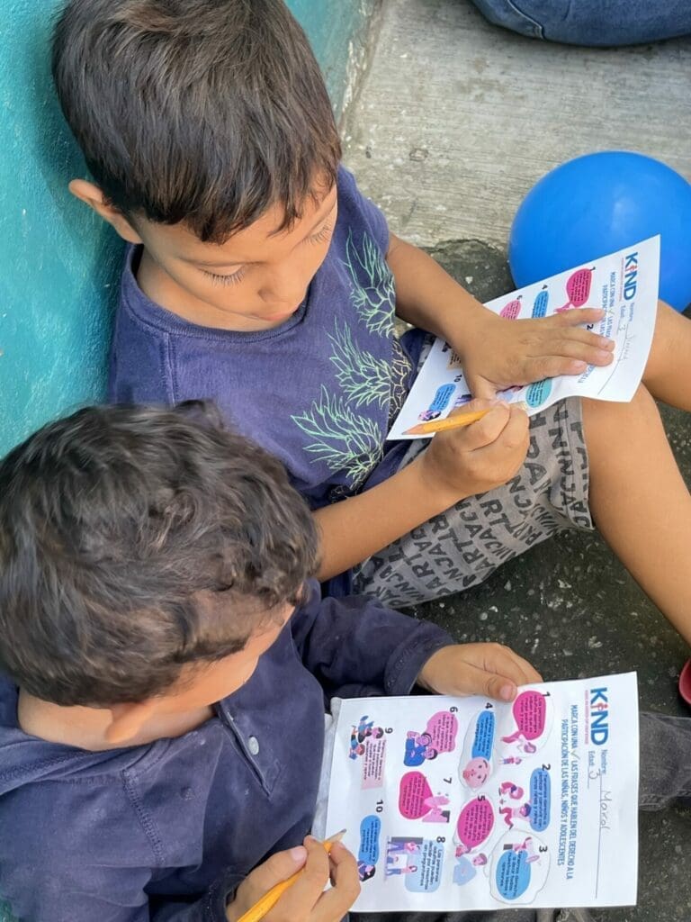 Two  boys sitting and reading a KIND KYR sheet
