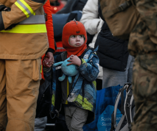 A child looks at a soldier while waiting for further transport after crossing the Ukrainian border with Poland in Medyka, southeastern Poland on March 14, 2022. - Over 2.8 million refugees have fled Ukraine since the invasion began, more than half going to Poland, according to the UN refugee agency. (Photo by Louisa GOULIAMAKI / AFP) (Photo by LOUISA GOULIAMAKI/AFP via Getty Images)