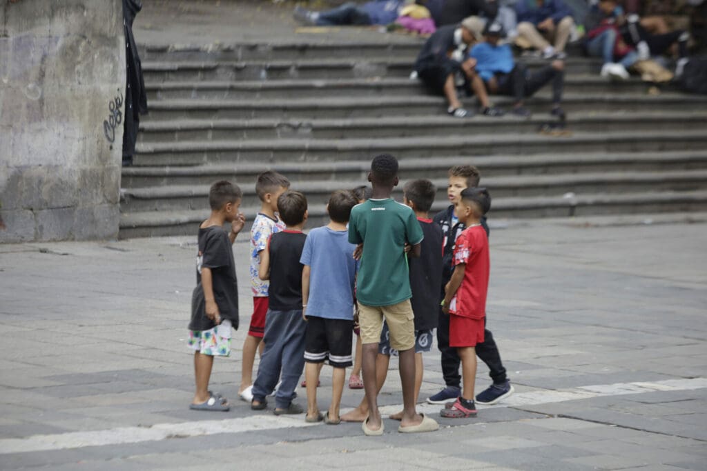A group of migrant children huddled together in a city.