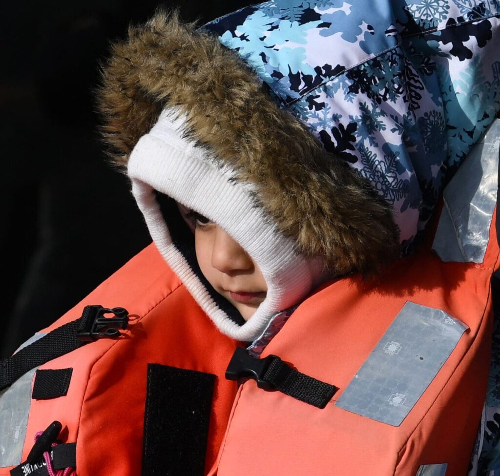 A child, picked up at sea while crossing the English Channel from France, holds the hand of an adult, after disembarking from a UK Border Force boat at the Marina in the Dover port, on May 3, 2022, in Dover, on the south-east coast of England.