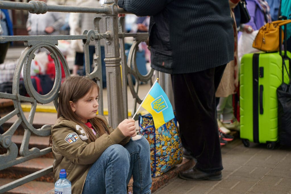 A young girl with a Ukrainian flag waits for a train heading